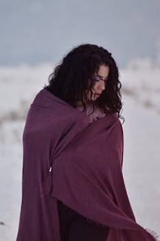 白雪皑皑的冬日背景中，一位优雅的女人裹着紫色围巾