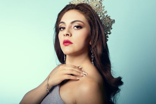 Free A regal woman adorned with a crown and jewelry, showcasing elegance in a studio setting. Stock Photo