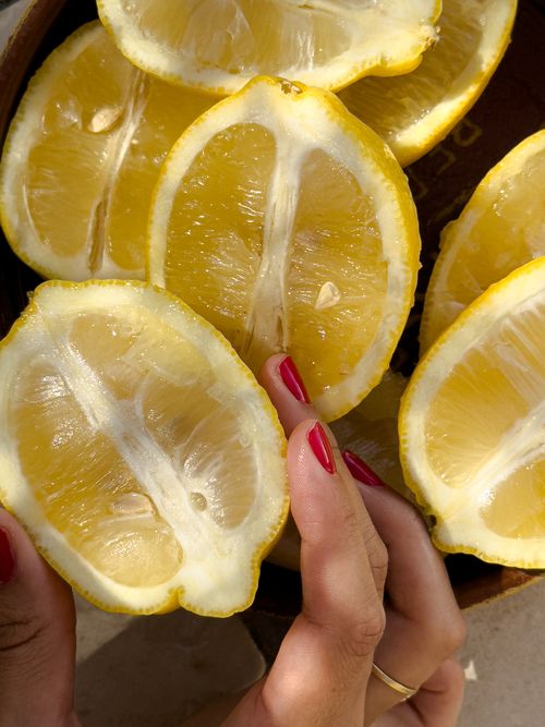Free Vibrant yellow lemon halves held by hands with red nails, perfect for food and lifestyle imagery. Stock Photo