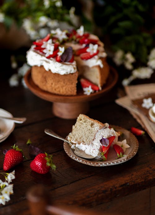 A Slice of Cake Lying on a Plate next to a Whole Cake on a Stand 