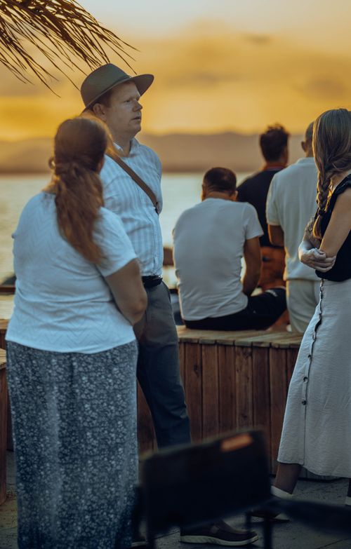 Free A group of adults enjoying a tropical sunset by the sea, creating a warm and relaxed atmosphere. Stock Photo