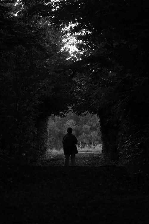 Free A dramatic black and white photo of a person silhouetted beneath a natural archway in Ghent, Belgium. Stock Photo