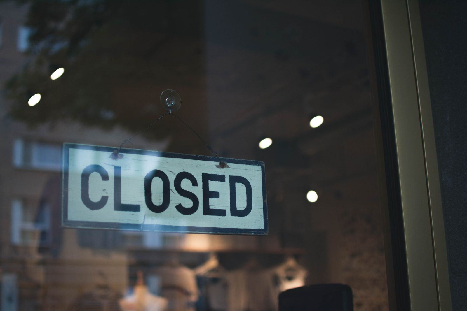 A CLOSED sign hanging on the glass door of a shop after hours