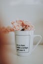 白色马克杯上印着励志名言，里面插着粉色人造玫瑰，营造出宁静的室内氛围