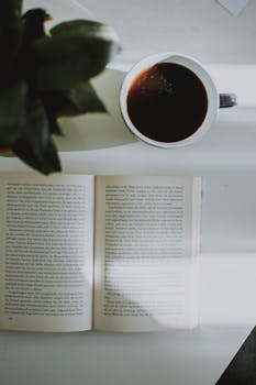 阳光明媚的桌上，一杯清咖啡和一本打开的书正适合在室内舒适阅读
