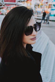 一个时尚的女人戴着太阳镜，在晴朗的户外摆着姿势