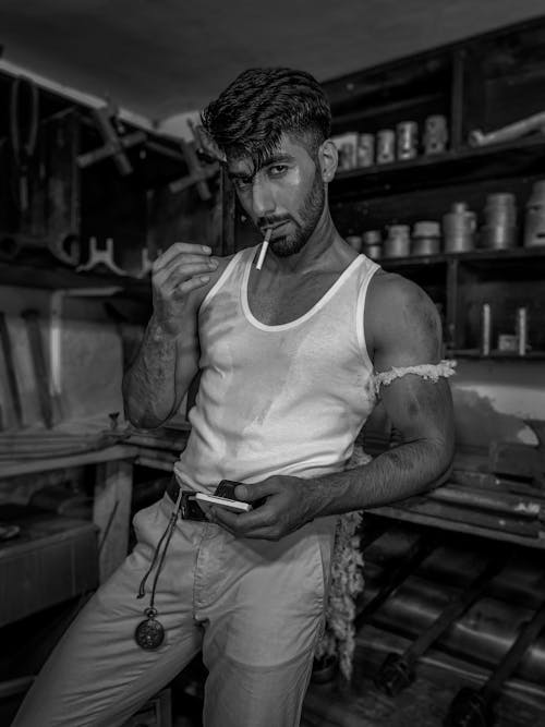 Man in Tank Top and with Cigarette in Workshop