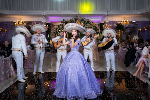 Woman in Purple Dress and Band in Traditional Clothing and in Sombreros