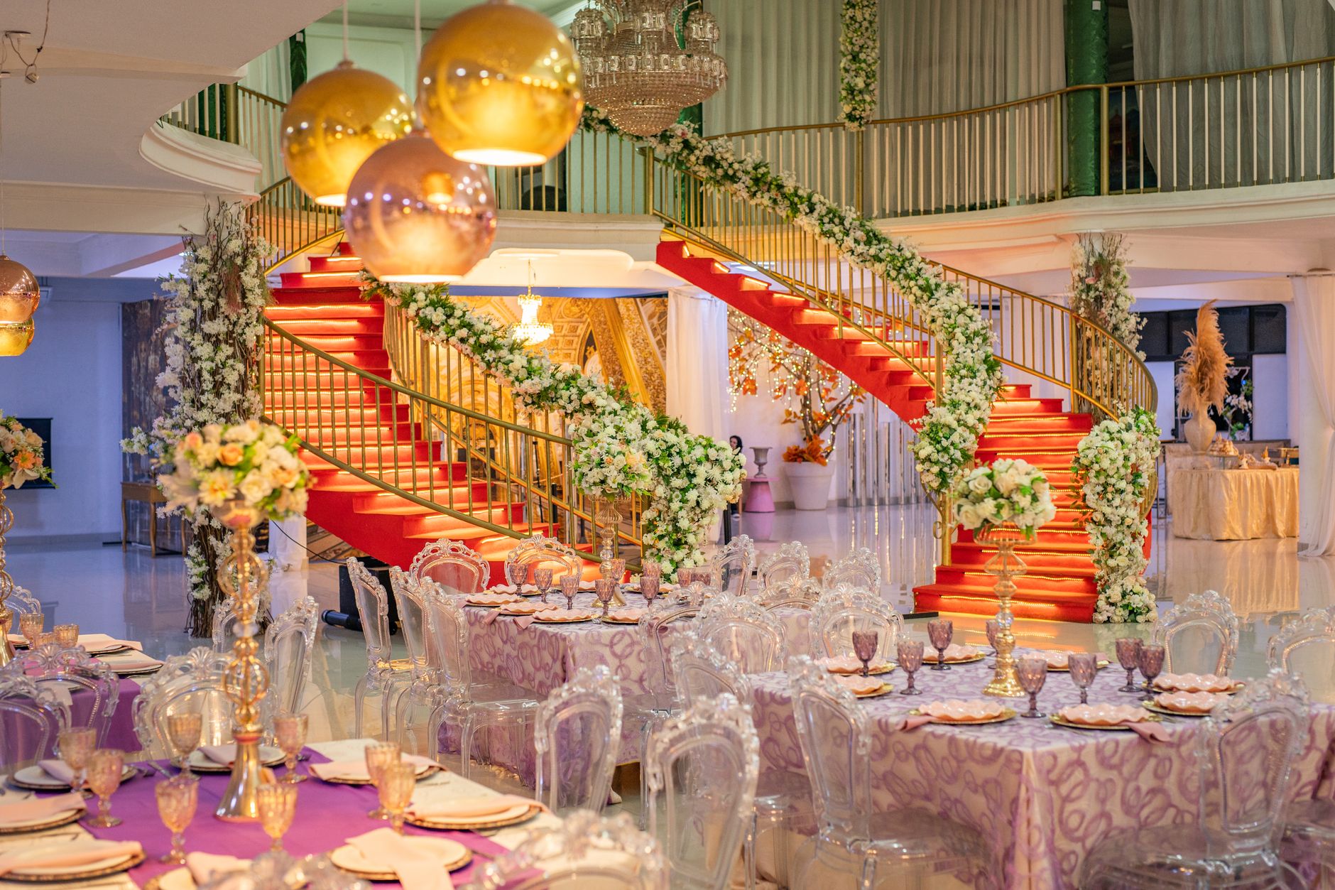 Luxurious indoor wedding venue featuring a floral-adorned grand staircase and elegant table settings.