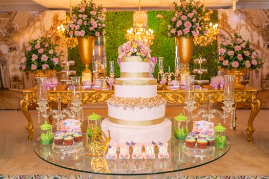 A beautifully decorated quinceañera venue featuring a lavish cake and floral arrangements with golden accents.