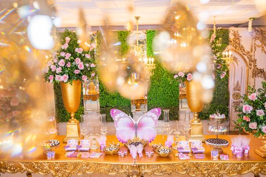 Luxurious butterfly-themed party table with floral arrangements and sweets. Perfect for special occasions.