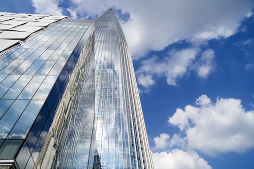 Low Angle Shot of a Glass Building against Blue Sky with White Clouds