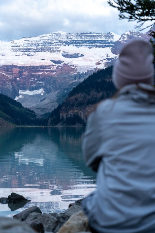 Back View of Woman Sitting by the Lake Louise and Looking at Snowcapped Mountains 