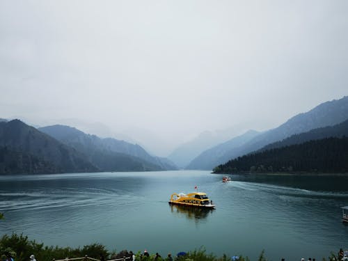 Free Mountain Landscape in Mist and a Yellow Boat on the Turquoise Water Stock Photo