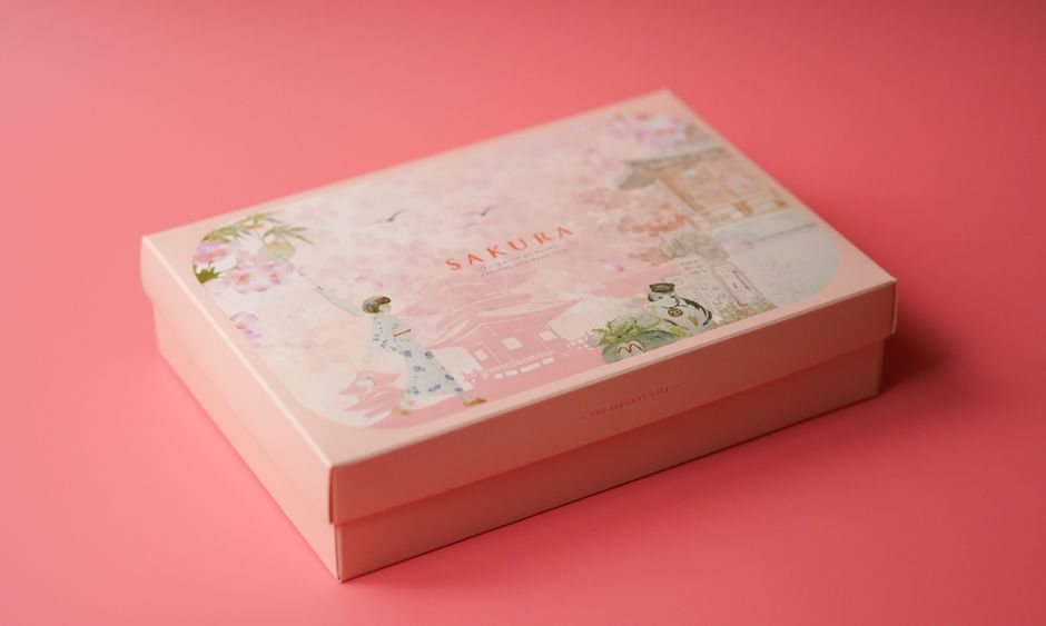 A beautifully designed Sakura gift box with floral illustrations on a soft pink background.