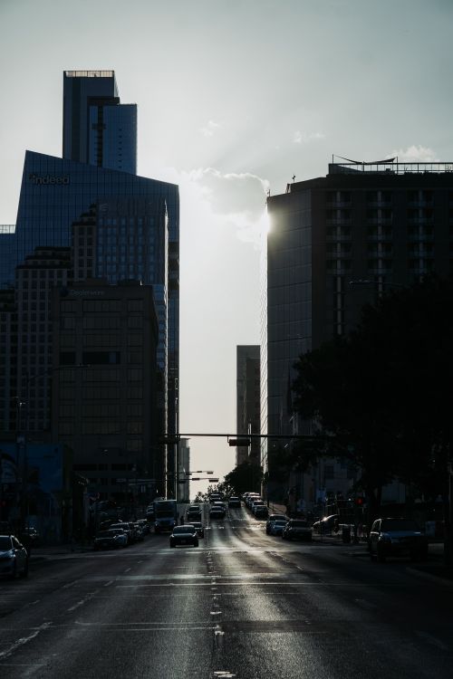 Free Downtown city street view with silhouette skyline against the morning sun. Stock Photo