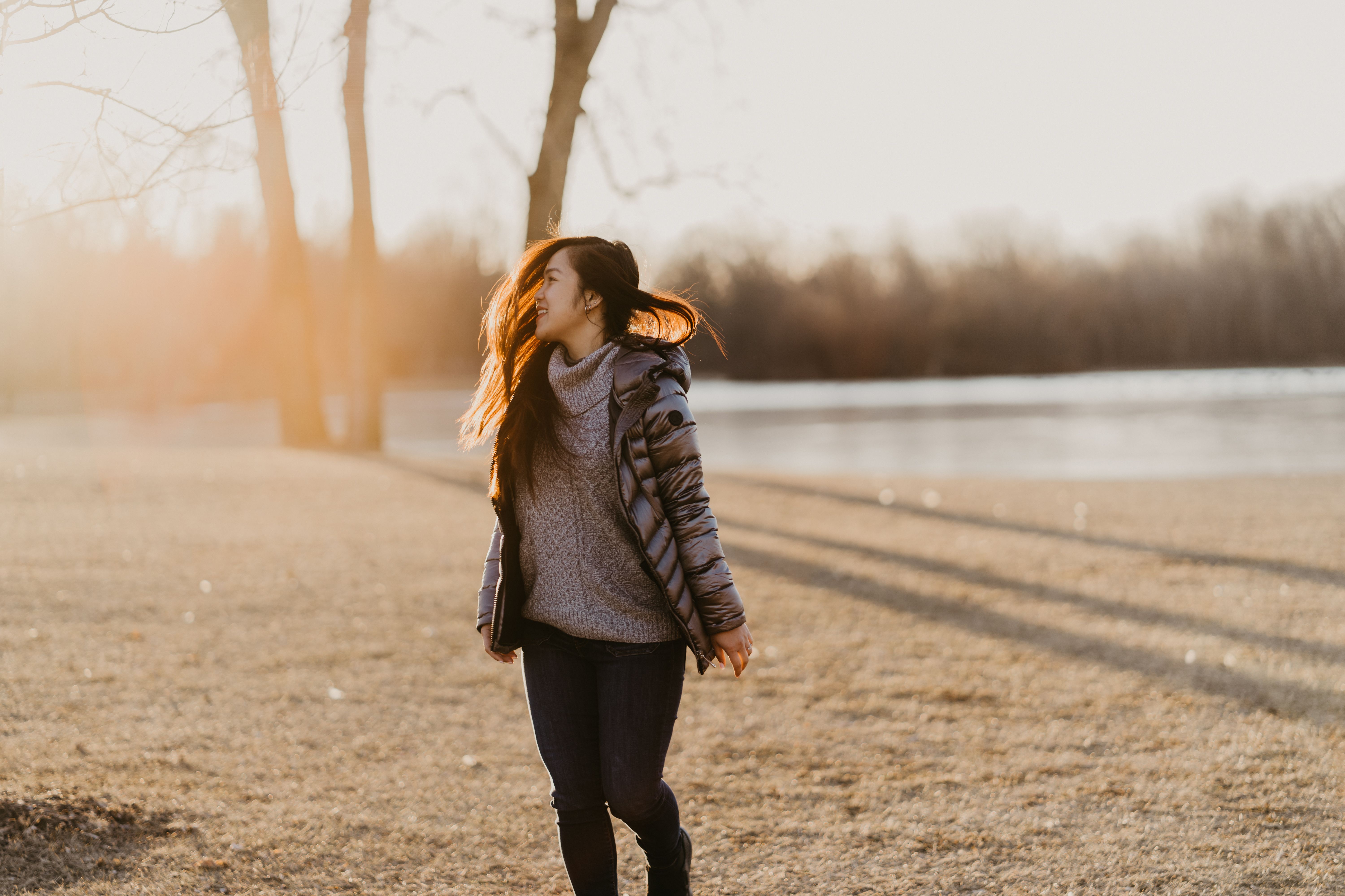 Young woman walking in a winter park, smiling and enjoying the sunny day.