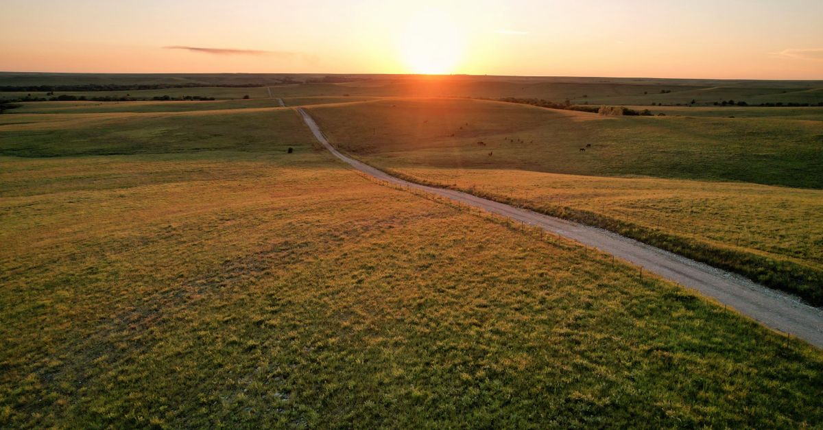 A serene sunset over rural fields with a winding dirt road in Eureka, Kansas.