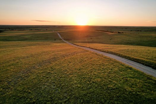 A serene sunset over rural fields with a winding dirt road in Eureka, Kansas.