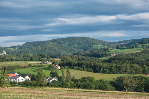 Free Beautiful rural landscape with fields, trees, villages, and rolling hills under a cloudy sky. Stock Photo
