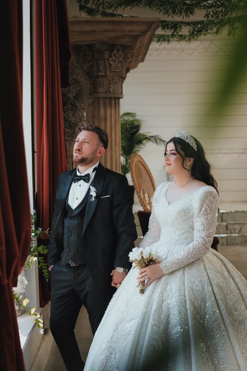 Free Bride and groom in elegant attire posing by a window at their wedding in Ankara, Türkiye. Stock Photo