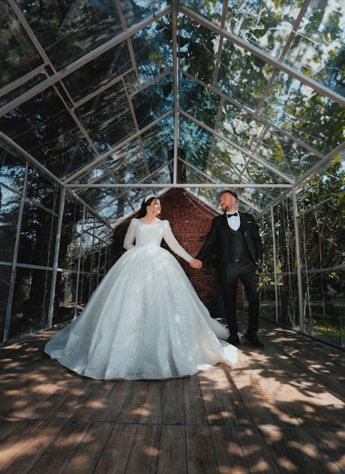Newlywed Couple Stand in Greenhouse