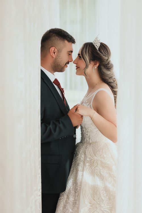 Free Charming wedding portrait of a couple sharing a tender moment indoors. Stock Photo
