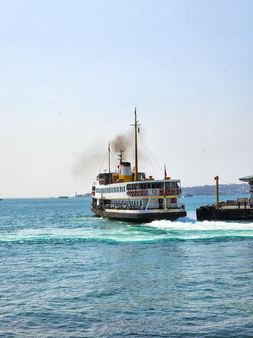 Free A passenger ferry departs from Istanbul pier, creating waves in the bright blue sea. Stock Photo