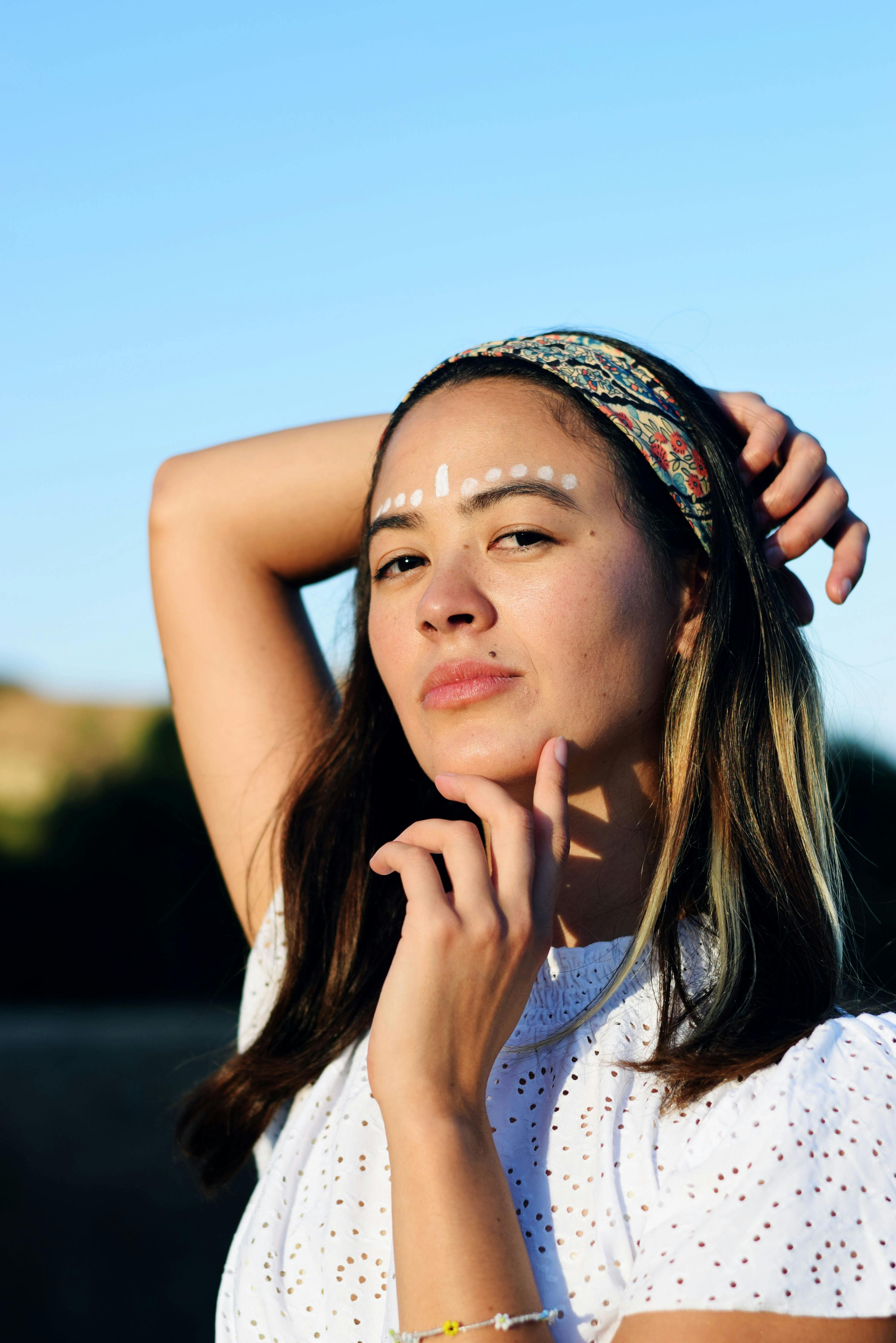 woman-with-white-dots-on-forehead-leaning-head-on-hand-free-stock-photo