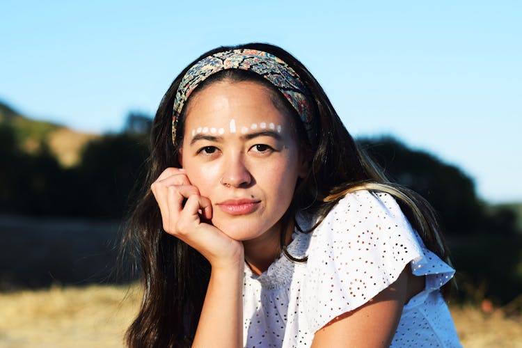 Woman With White Dots On Forehead Leaning Head On Hand