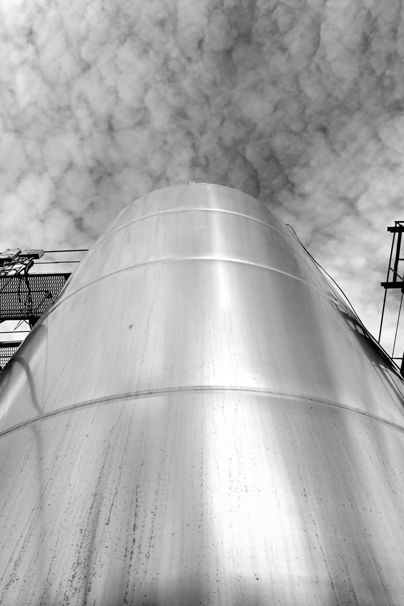 A striking black-and-white photo of a steel silo with a cloud-filled sky in Ukraine.