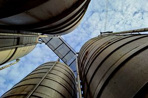 Storage silos seen from below against a bright sky — photo by Oleh Budurov on Pexels