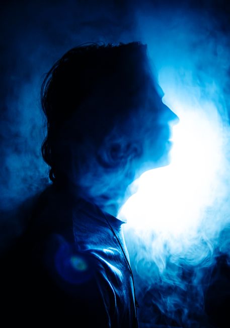 A captivating silhouette of a person against a blue smoky background, creating a mystical mood.