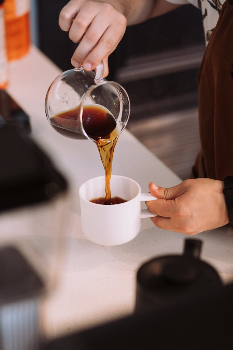 Man Pouring Coffee From A Glass Carafe