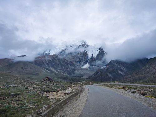 Free A winding road leading to a snow-capped mountain in North Sikkim, India under cloudy skies. Stock Photo