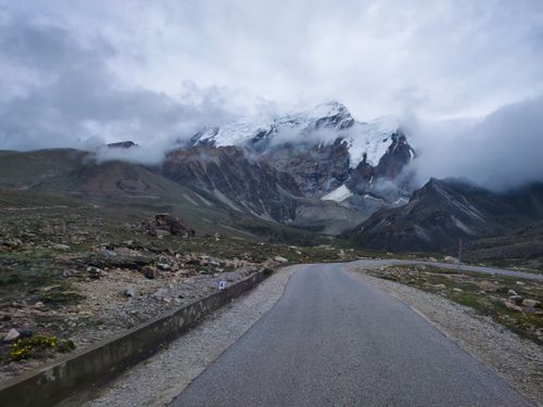 Free A curving road under cloudy skies leads to the snowy mountains of North Sikkim, India. Stock Photo