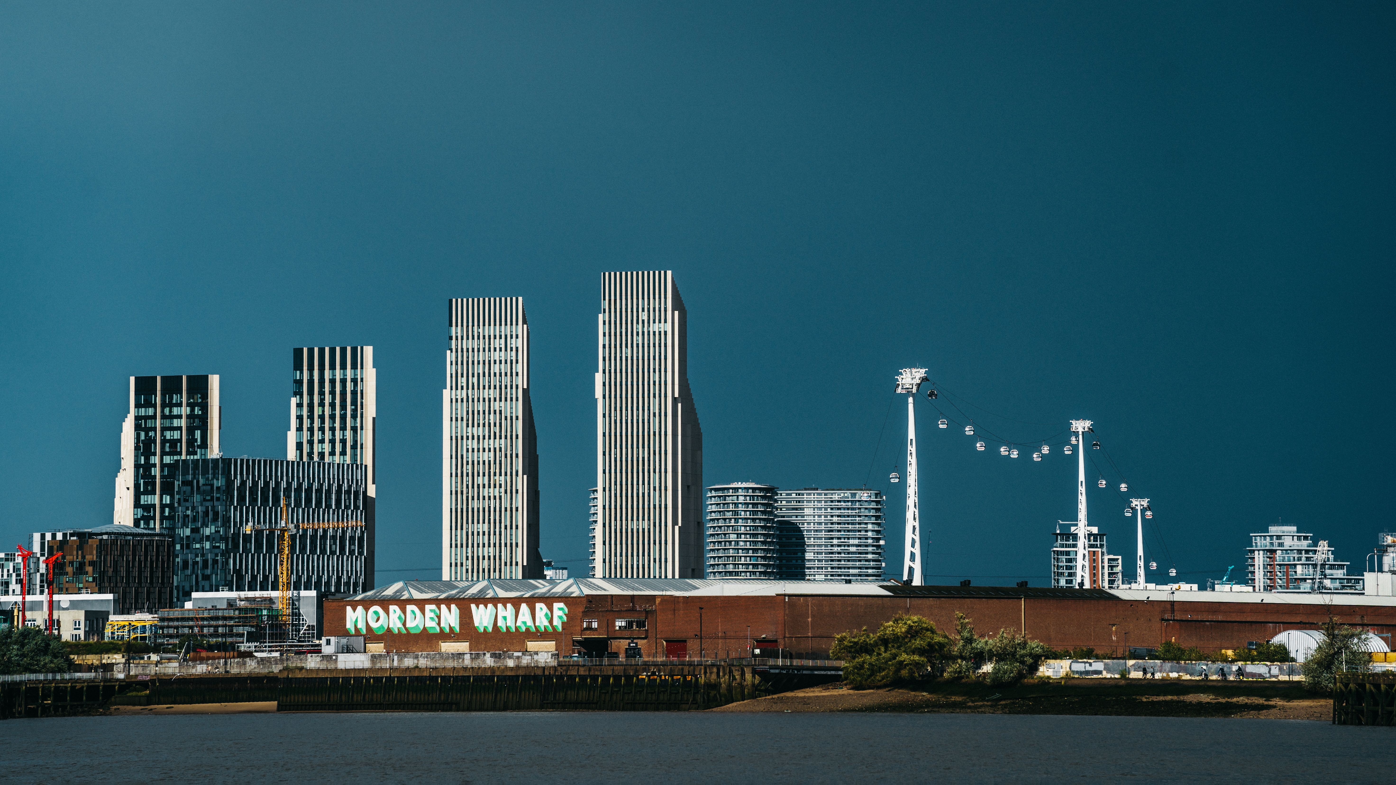 View of London skyline featuring modern skyscrapers and the Morden Wharf area by the river.
