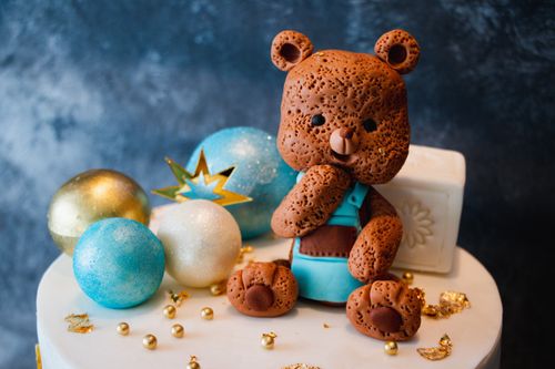 Free Adorable teddy bear cake topper surrounded by glittery spheres and a festive design, perfect for celebrations. Stock Photo