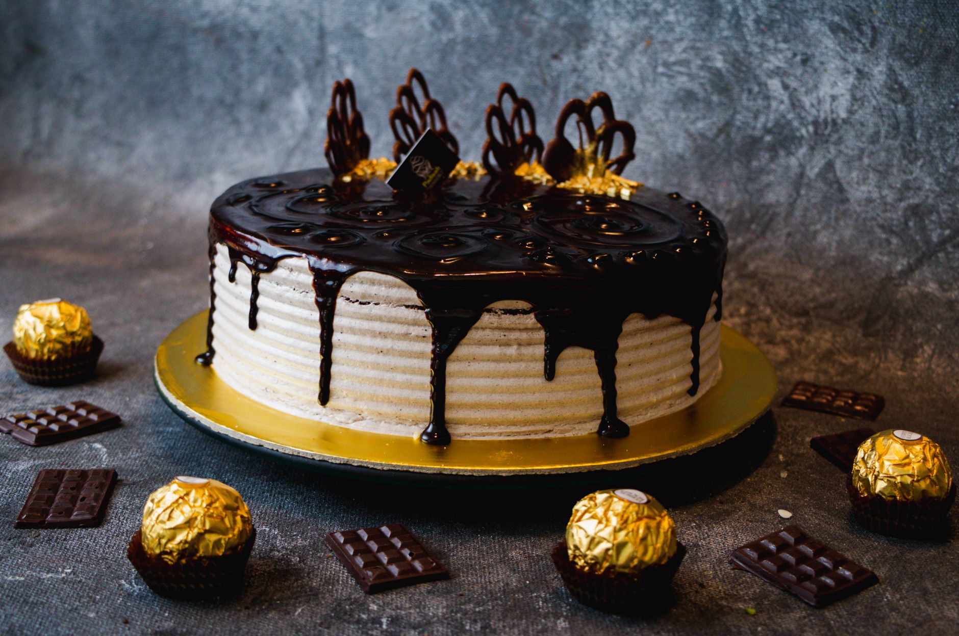 Delicious chocolate drip cake adorned with Ferrero Rocher and chocolate pieces, perfect for celebrations.