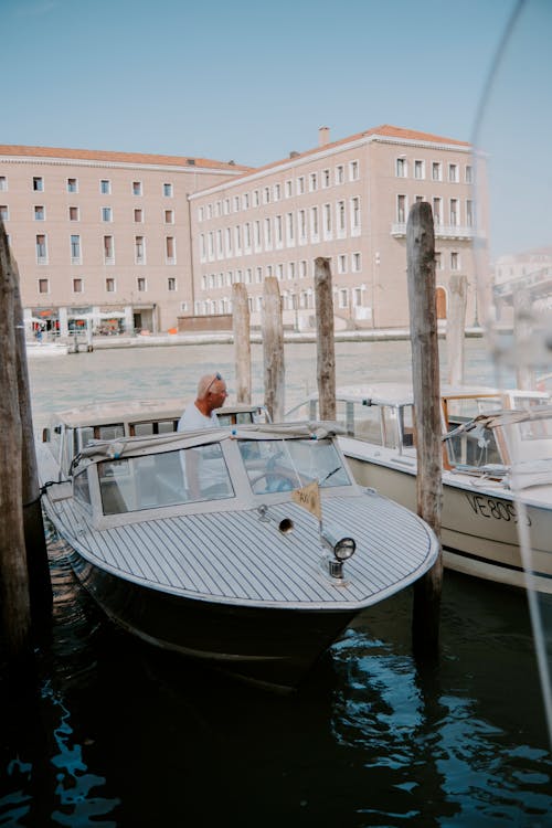 Man Standing in a Motorboat Moored at Marina in Venice, Italy
