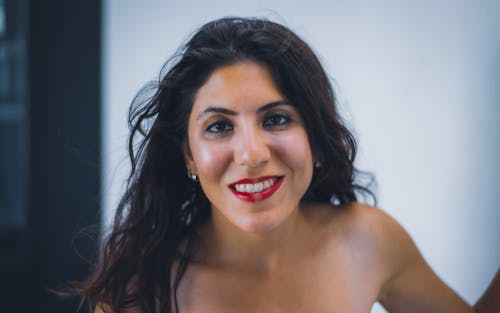 Photo of a Young Smiling Woman with Red Lips and Tousled Hair 