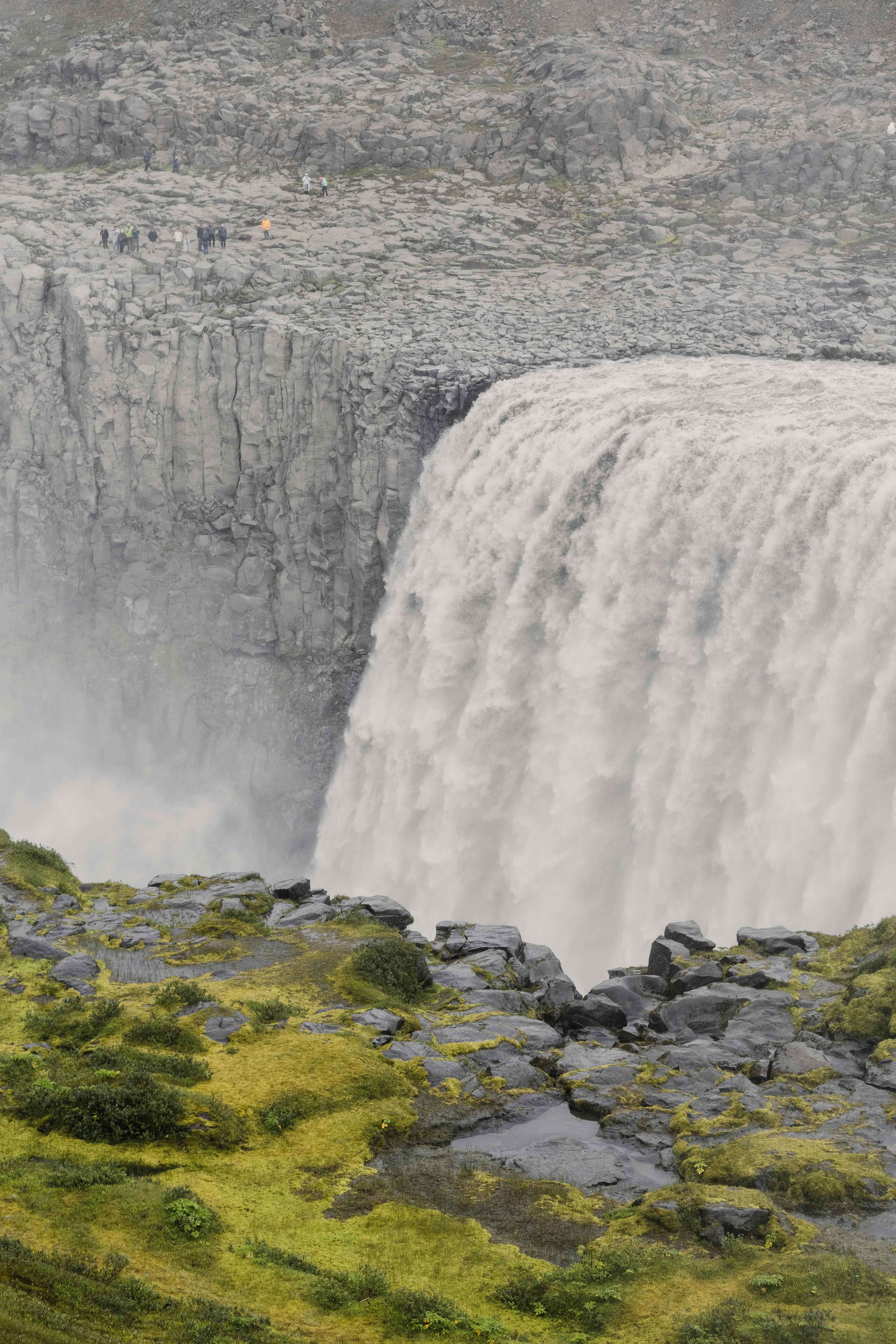 Breathtaking view of a powerful waterfall surrounded by rocky cliffs and lush moss in Iceland.