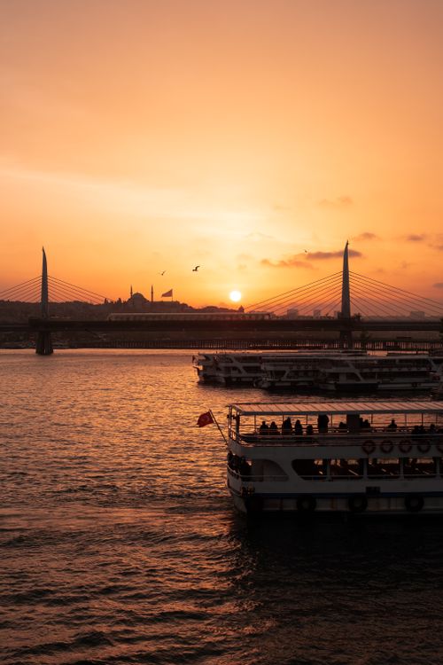 Free Stunning sunset view over Istanbul's Bosphorus, highlighting ferries and bridge silhouettes against warm skies. Stock Photo