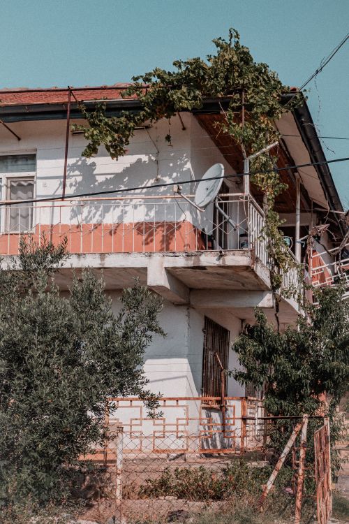 Free A rustic house with vibrant balcony and climbing vines under a clear sky. Stock Photo
