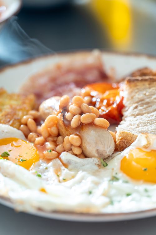 Free Enjoy a mouthwatering Full English breakfast with eggs, sausage, beans, and toast. Stock Photo