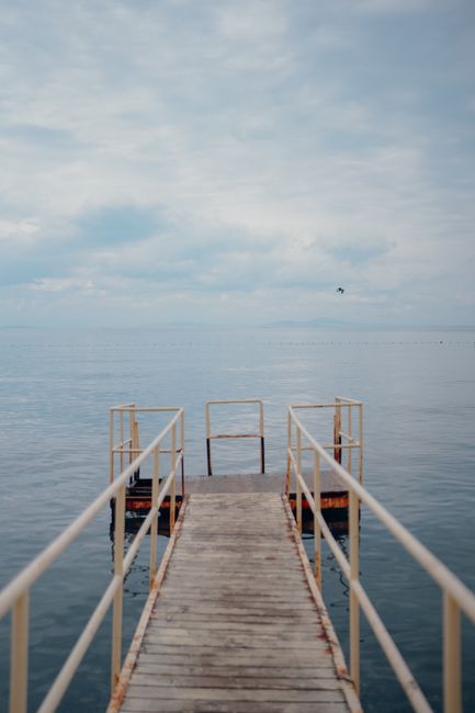 Serene view of a wooden pier extending into a calm sea under a cloudy sky, evoking a sense of peace.
