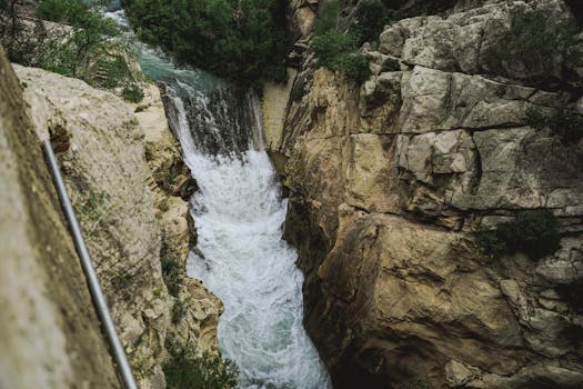 Breathtaking view of a waterfall cascading through rocky cliffs in Caminito del Rey, Spain.