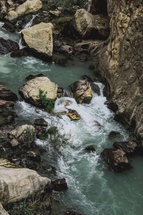 Free A tranquil river cascades through rugged rocks in a lush outdoor setting. Stock Photo