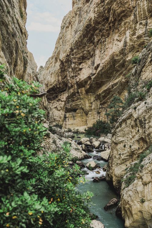 Free Breathtaking view of a narrow gorge with a flowing river and lush greenery in Ardales, Spain. Stock Photo
