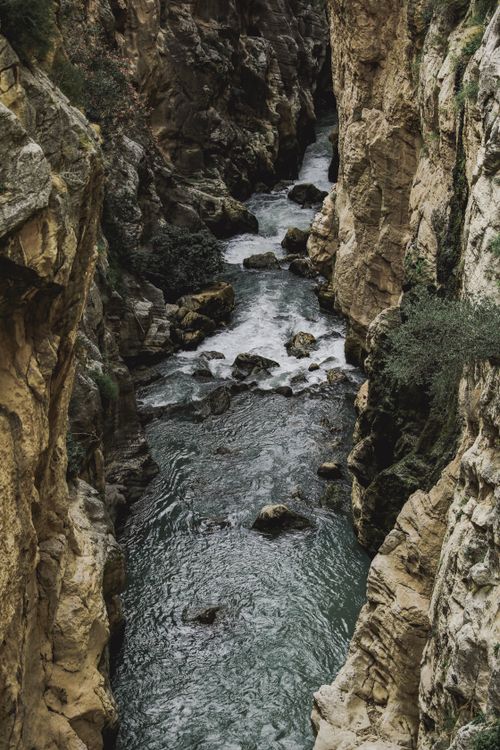 Free A captivating view of a river flowing through a narrow canyon surrounded by rocky cliffs and lush vegetation. Stock Photo